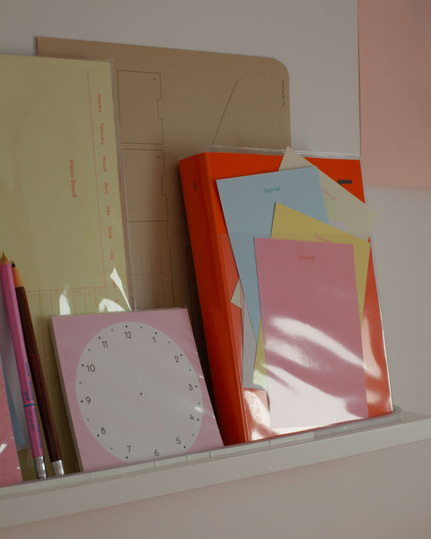 Shelf displaying colorful stationery items and various planners by Fluo.