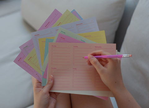 Person holding colorful weekly planner memo sheets by Fluo and a pink mechanical pencil by Mark's Inc