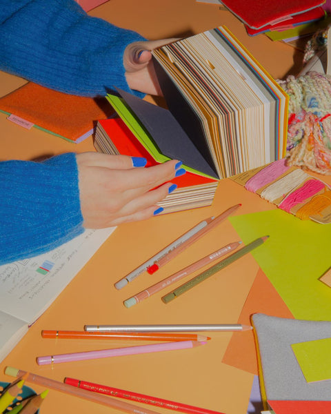 A person wearing a bright blue jumper flipping through the G. F. Smith collection book.