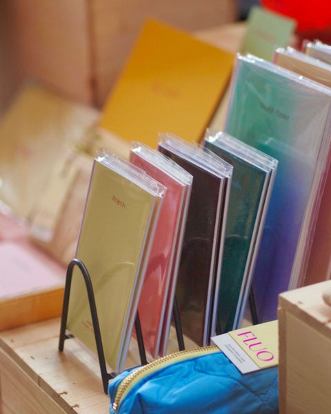 Stacks of colorful notebooks neatly displayed at a market stand table