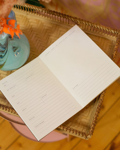 An open plant journal on a textured background with dried flowers in the foreground