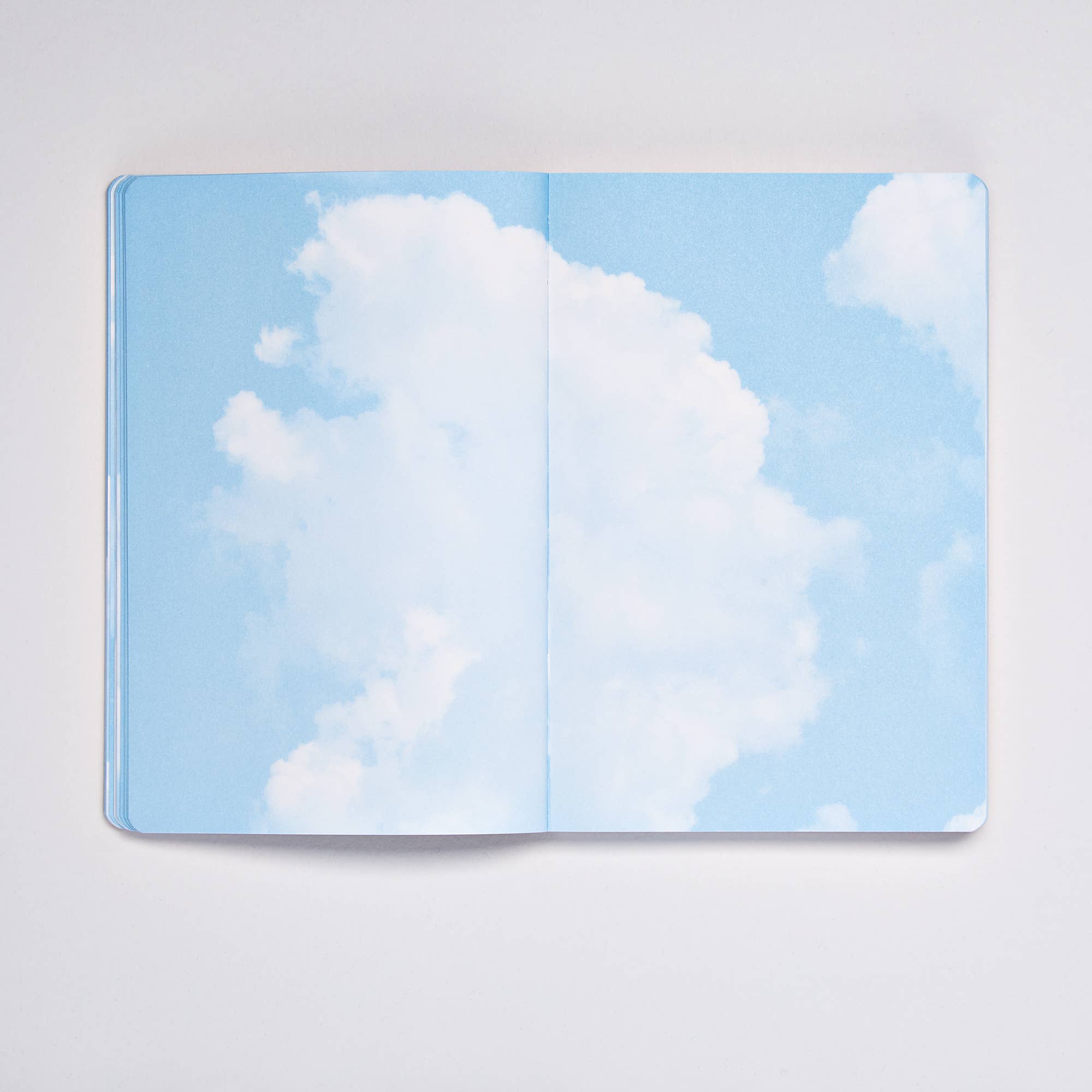 Open Clouds Junk Journal spread showing bright blue sky with fluffy white cumulus clouds