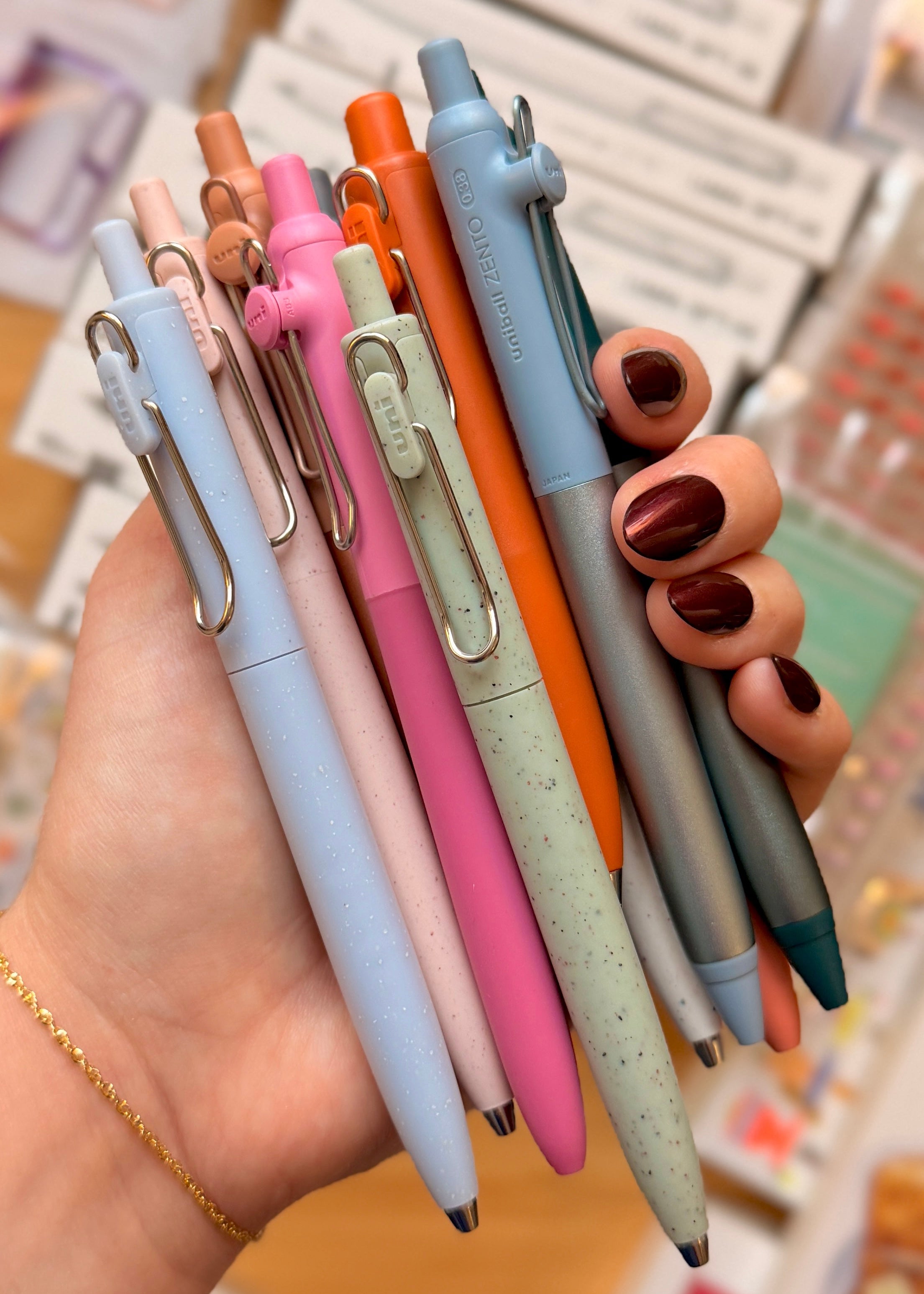 Hand holding a collection of colorful pens with a blurred background