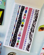 Open page of the junk journal sticker book with decorative border strips — lace, stars, red gingham, gemstones and foil