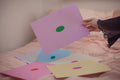Hand holding a pink sheet of paper with a green oval in the center, depicting a blank mind map. Surrounded by similar sheets in different color combinations.