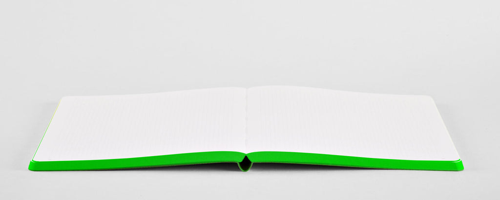 Open neon green bullet journal by Nuuna with colored edges, laying completely flat on a grey background