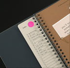 Spiral-bound notebook with an index page and a pink dot on a black background