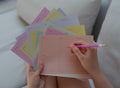 Person holding colorful weekly planner memo sheets by Fluo and a pink mechanical pencil by Mark's Inc